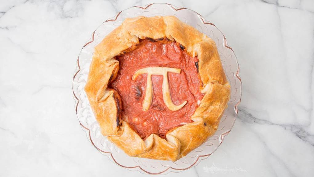 Pie with a pi symbol in the center made of crust, on a marble countertop.