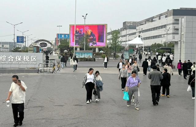 夕方、仕事のために鴻海（ホンハイ）精密工業の工場に向かう従業員と、仕事を終えて出てくる従業員=2025年4月21日、河南省鄭州市、鈴木友里子撮影