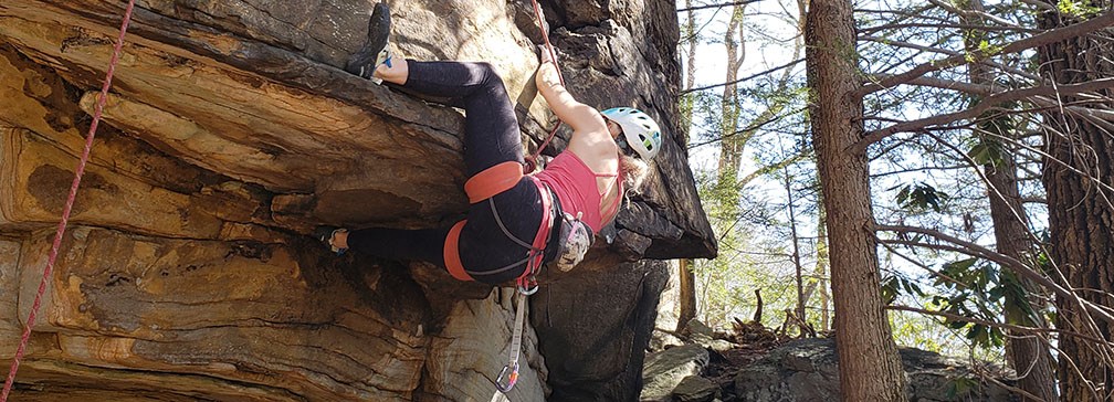 Female climber ascends a rock face